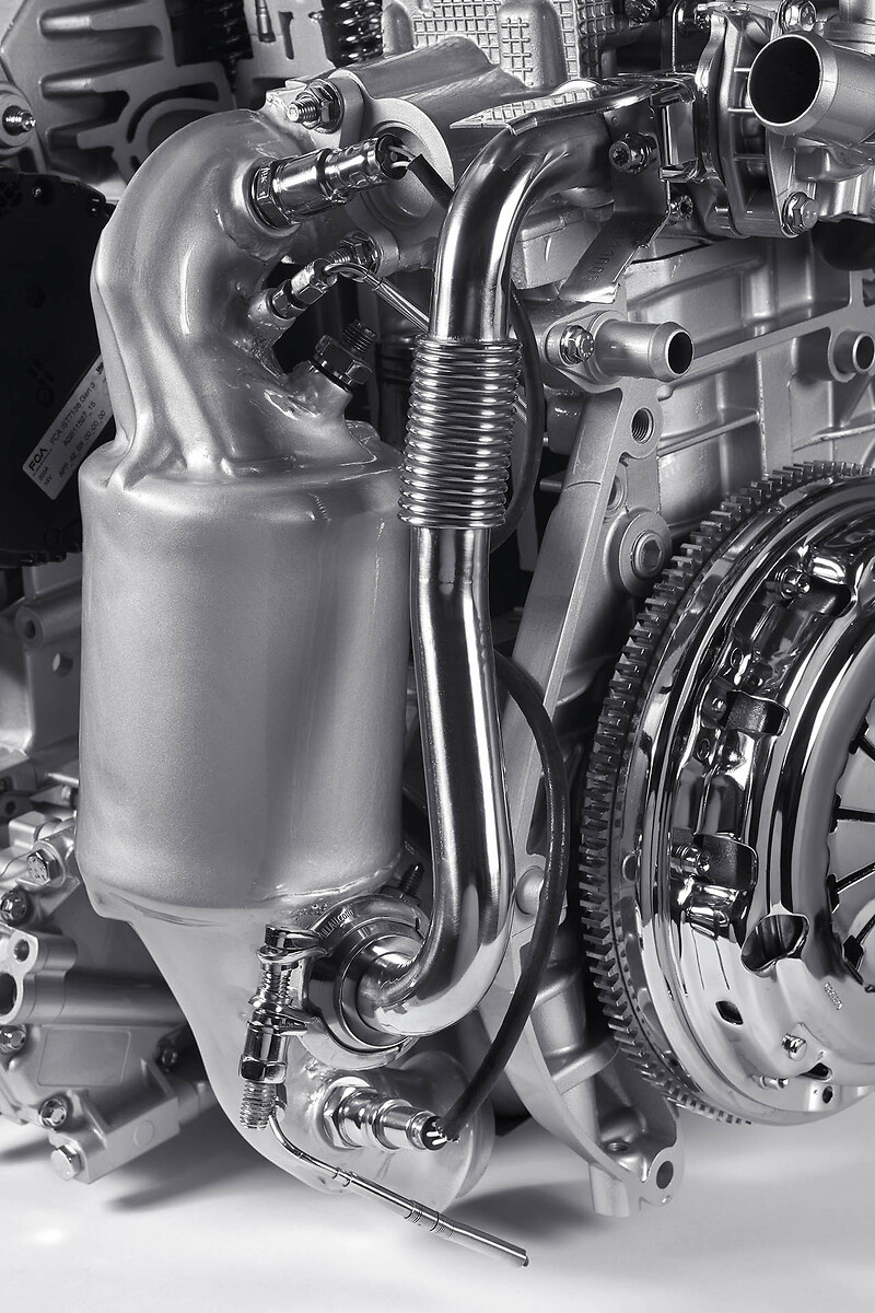 Katalyzátor a trubka vedúca do EGR ventilu. Zaujímavosťou je chladenie výfukových zvodov pred vstupom do katalyzátora. Vďaka tomu motor vo vysokých otáčkach nedochladzuje výfukové plyny benzínom a nepoškodzuje katalyzátor. Motor je preto úsporný aj na diaľnici.